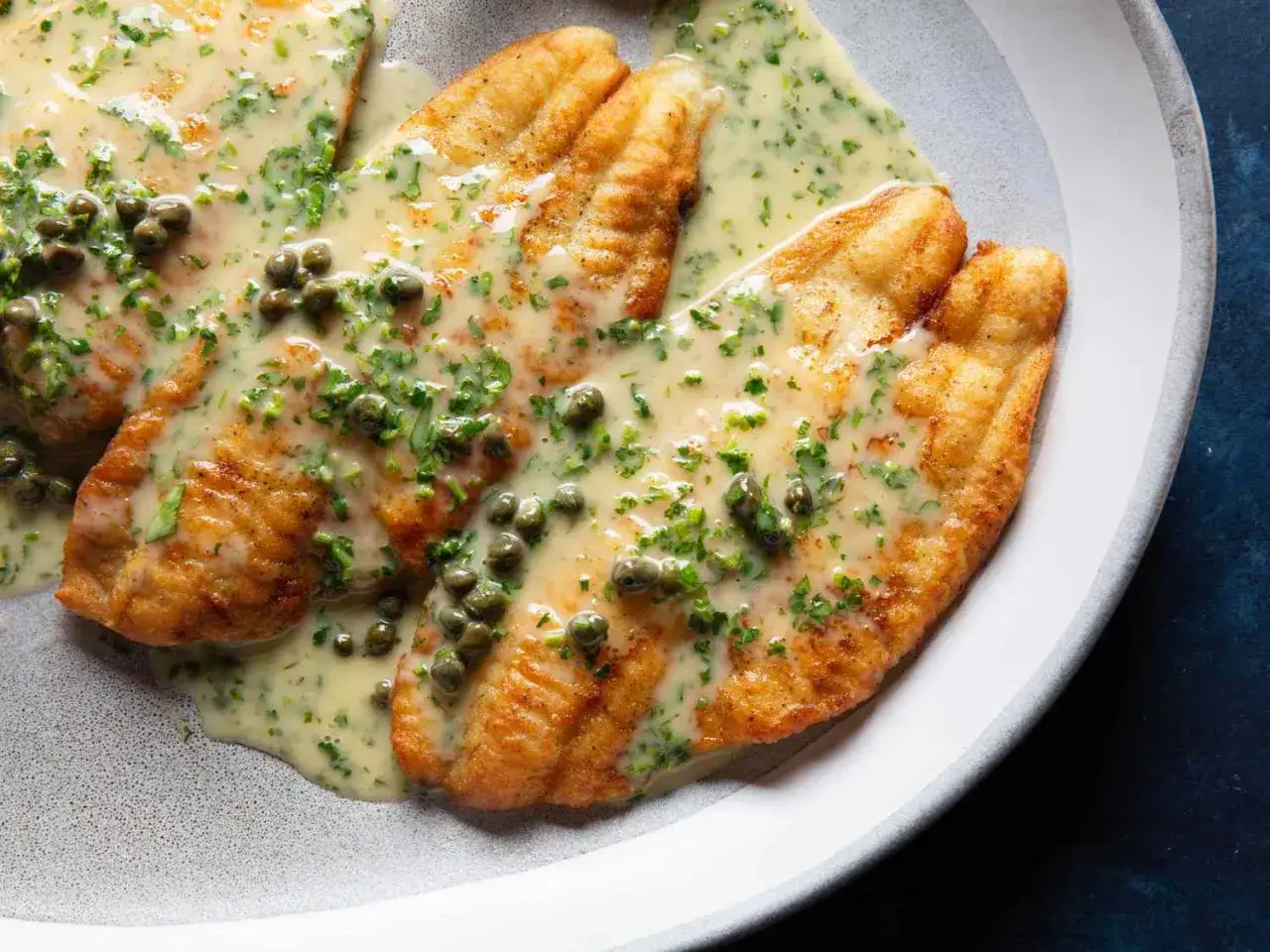 Filets de poisson dorés, nappés d'une sauce crémeuse aux câpres et persil. Un accompagnement poisson savoureux et élégant.