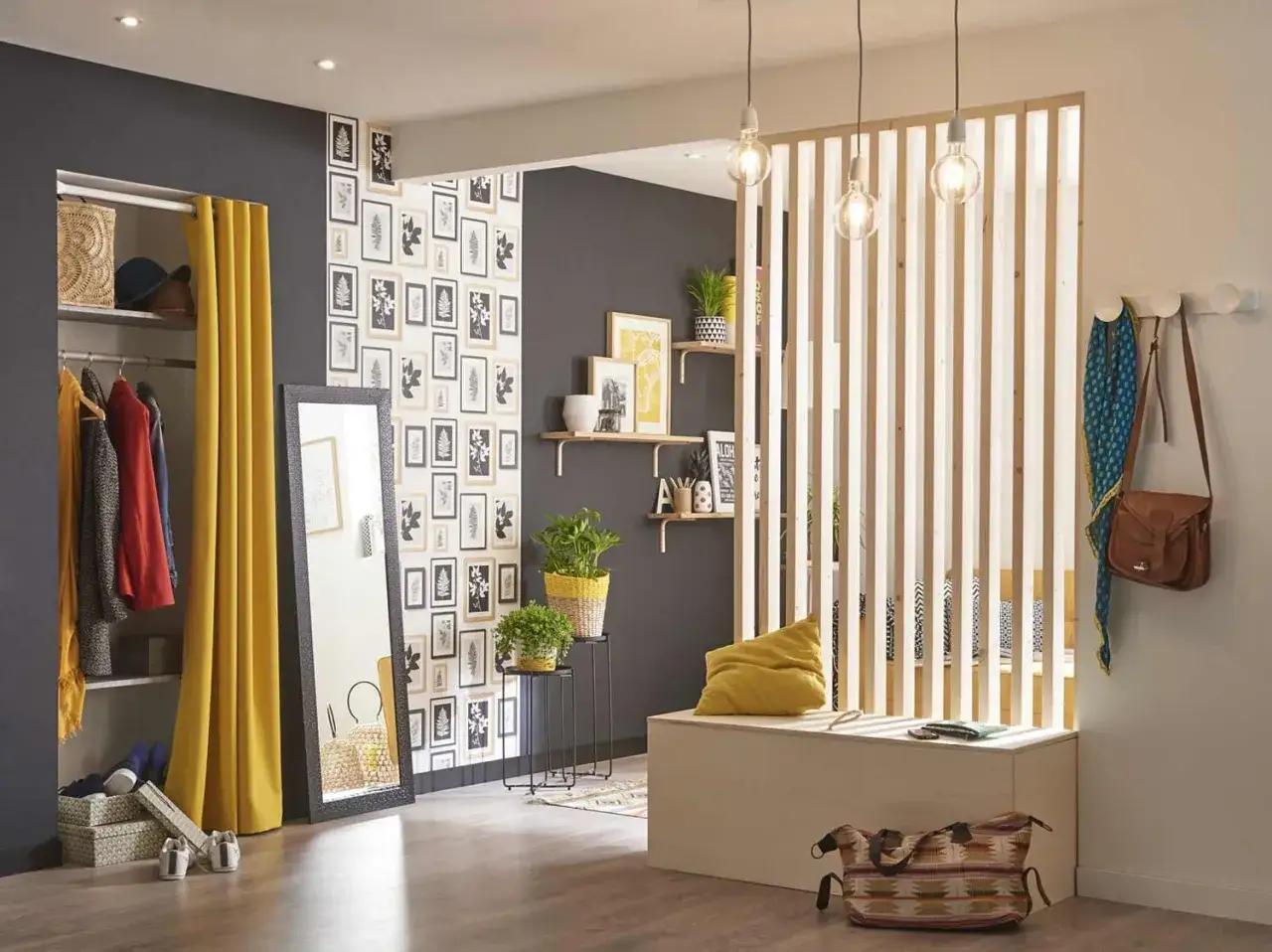 Un claustra int&eacute;rieur fait maison s&eacute;pare l'entr&eacute;e d'un dressing d'un coin salon. Des plantes et des cadres d&eacute;corent le mur.