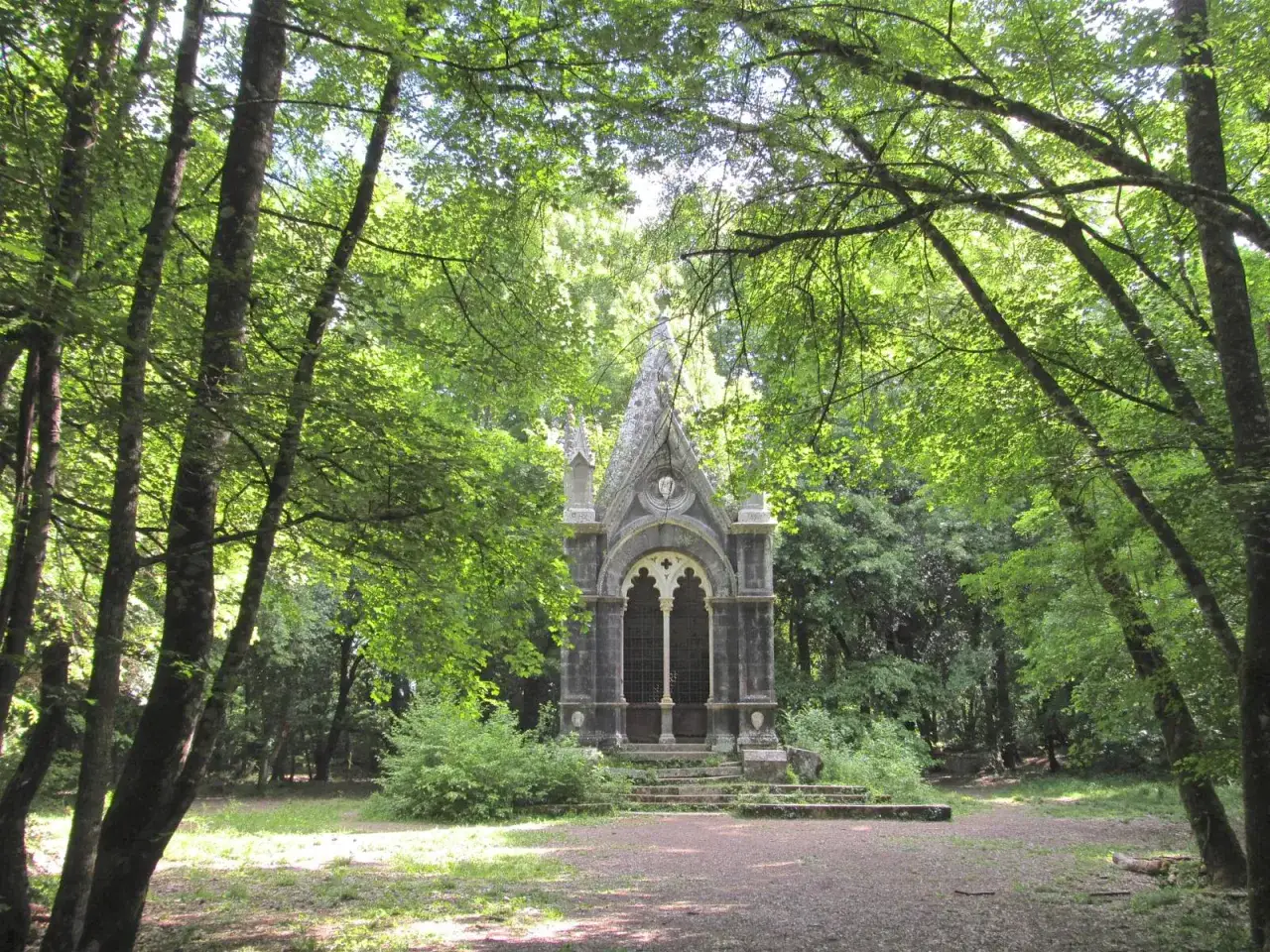 Un piccolo tempietto gotico nel **bosco delle fate Torre Alfina**, circondato da alberi rigogliosi e sentieri ombrosi.