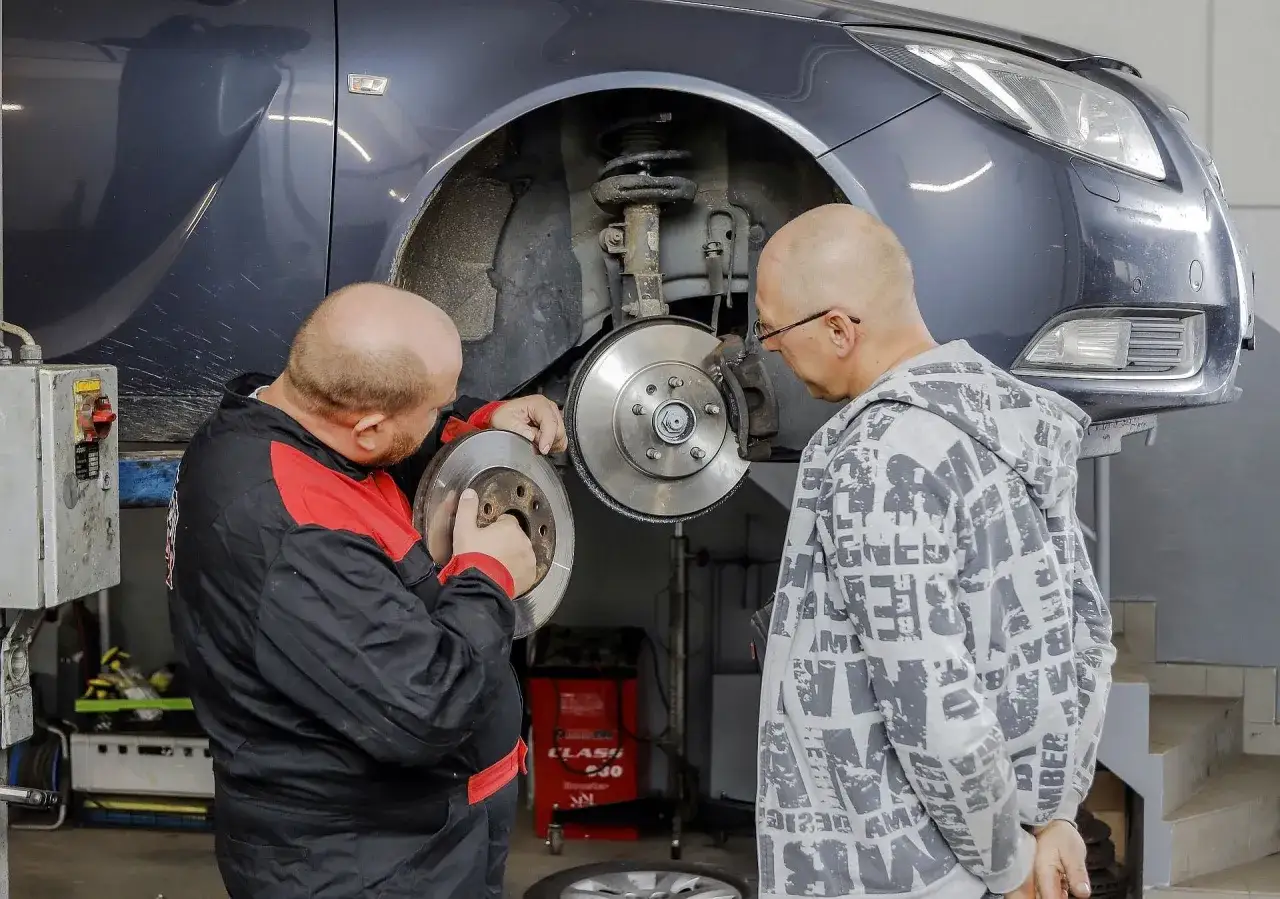 Mechanik pokazuje klientowi zużyty hamulec, który mógł powodować piszczenie w kole podczas wolnej jazdy.