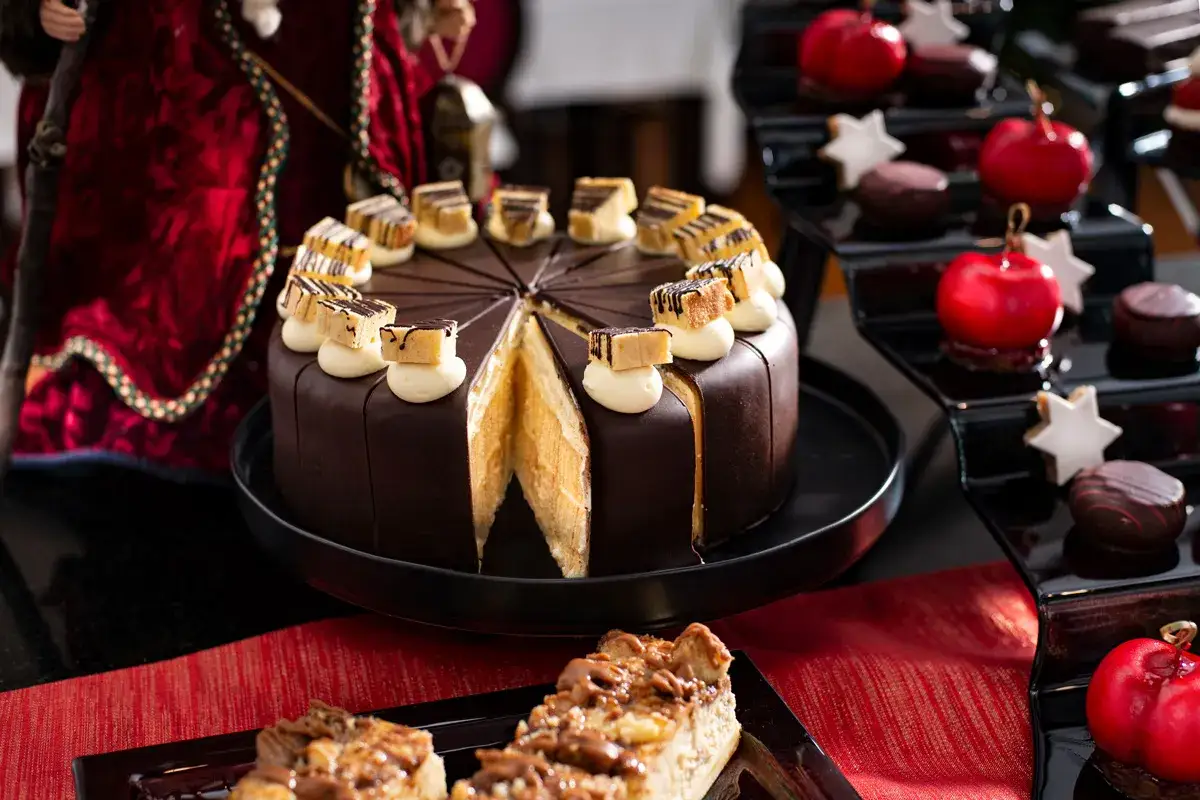 Schokoladenkuchen mit Sahnetupfern und Karamellstückchen, perfekt für den Adventskaffee. Daneben rote Äpfel und Sterne.