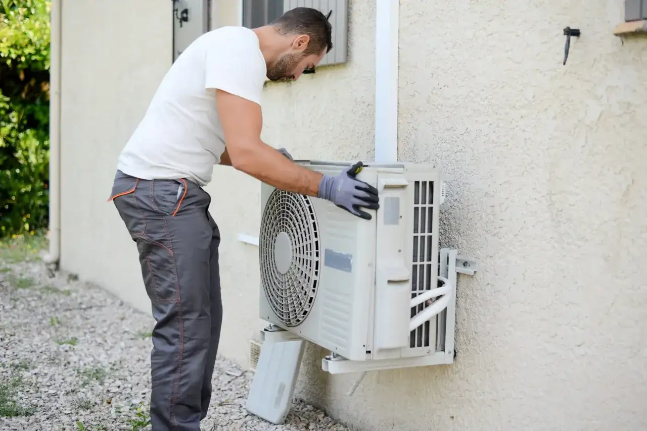 Un homme installe un clim à poser soi même sur un mur extérieur.