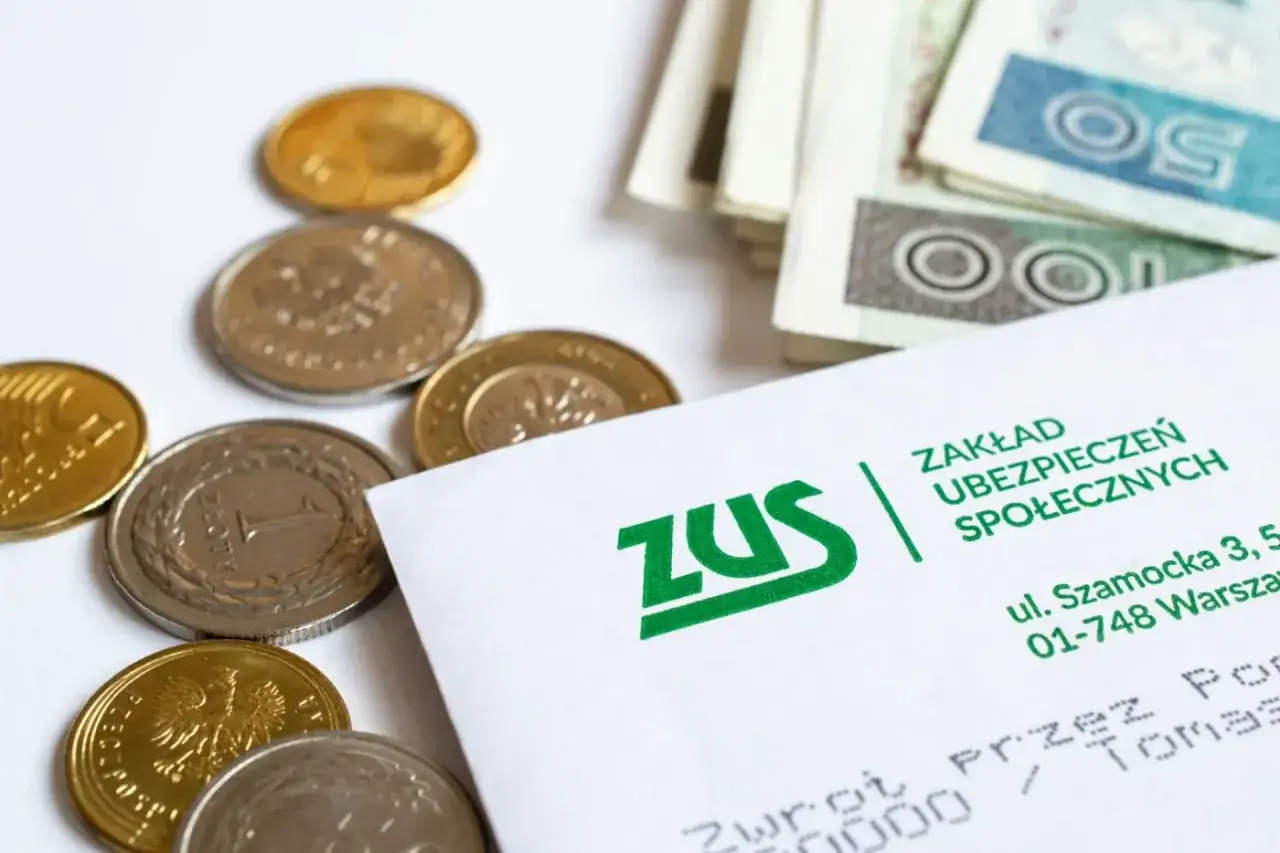 Monety i banknoty obok dokumentu ZUS. Tabela netto 14 emerytury może być kluczowa dla wielu seniorów.