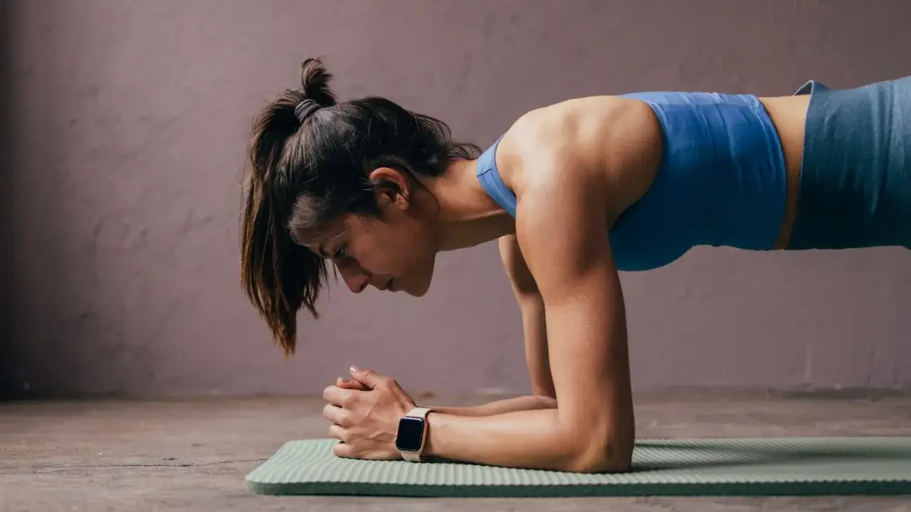 Femme en position de planche, travaillant ses **hips dips** sur un tapis de yoga.