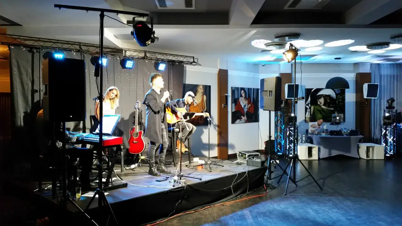 Odkryj sekrety produkcji: jak powstają aranżacje hitów do odgadywania po jednej nutce. Zespół na scenie, wokalista, gitarzysta, klawiszowiec i DJ.