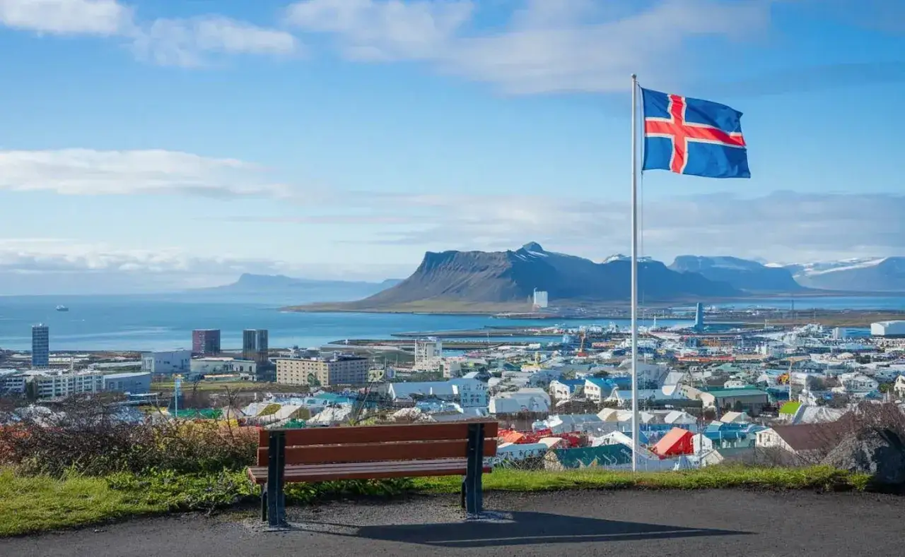 Widok na Reykjavík z ławką i flagą Islandii. Marzysz o pracy na Islandii? To miasto może być Twoim nowym domem.