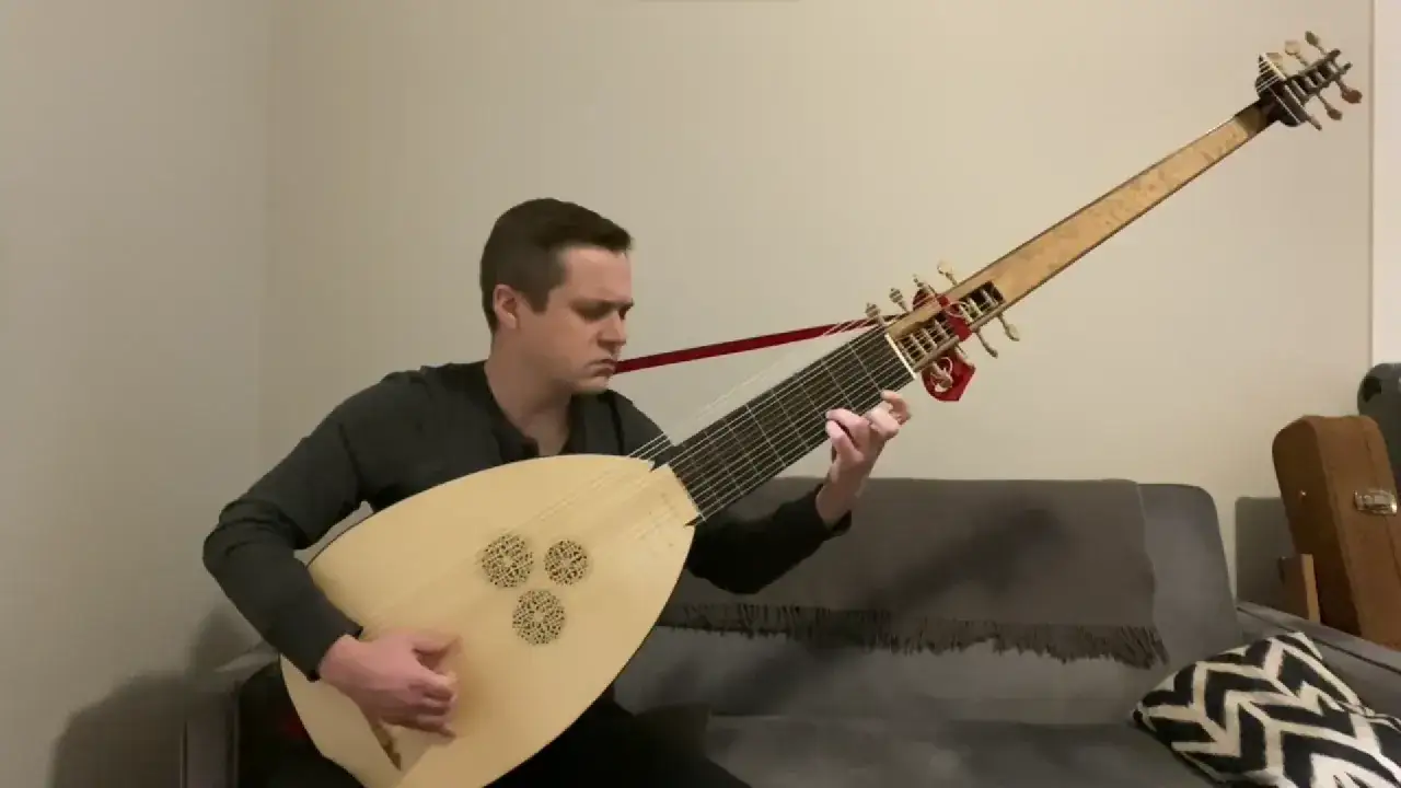 Mężczyzna gra na instrumencie strunowym podobnym do lutni, z długą szyjką i ozdobnym pudłem rezonansowym.