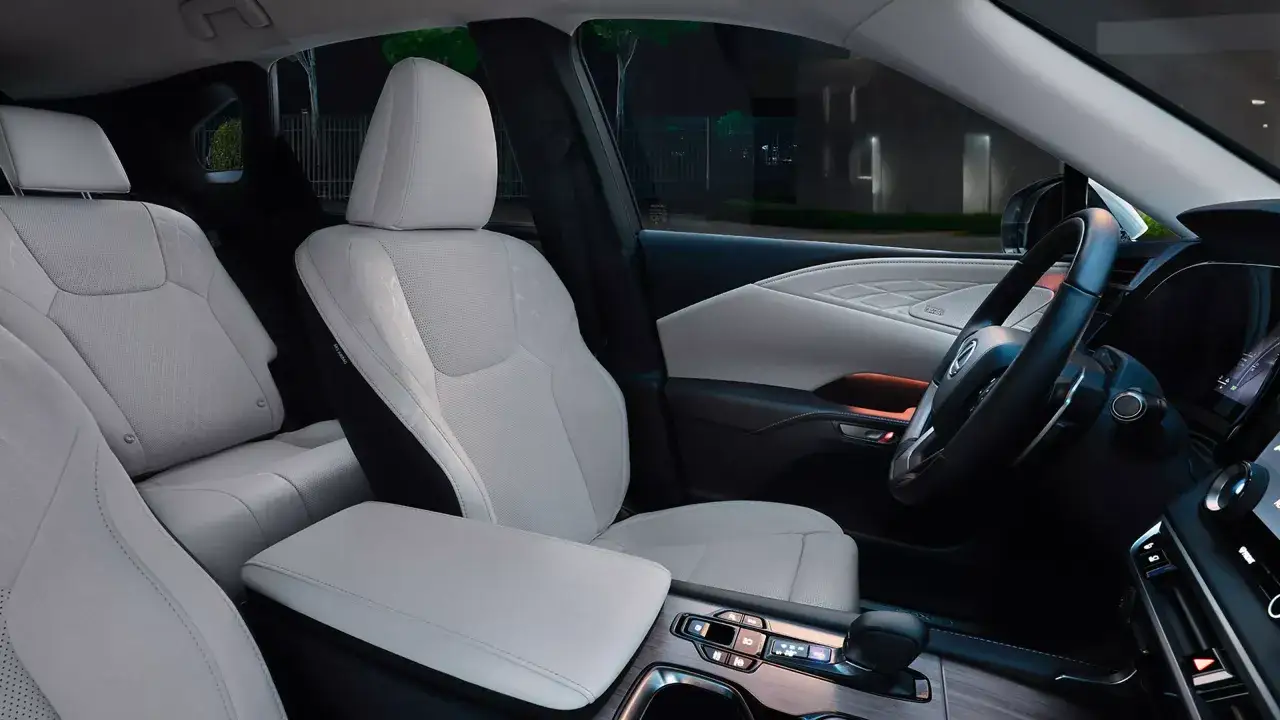 Wnętrze luksusowego SUV-a Lexus z jasnymi, pikowanymi fotelami i nowoczesną konsolą środkową.
