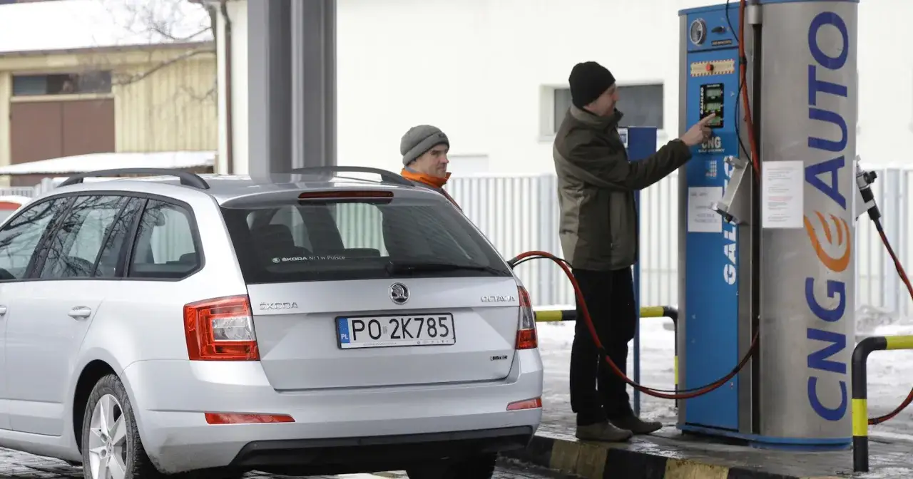 Mężczyzna tankuje samochód na stacji CNG. Widoczna jest dystrybutor z napisem CNG AUTO.