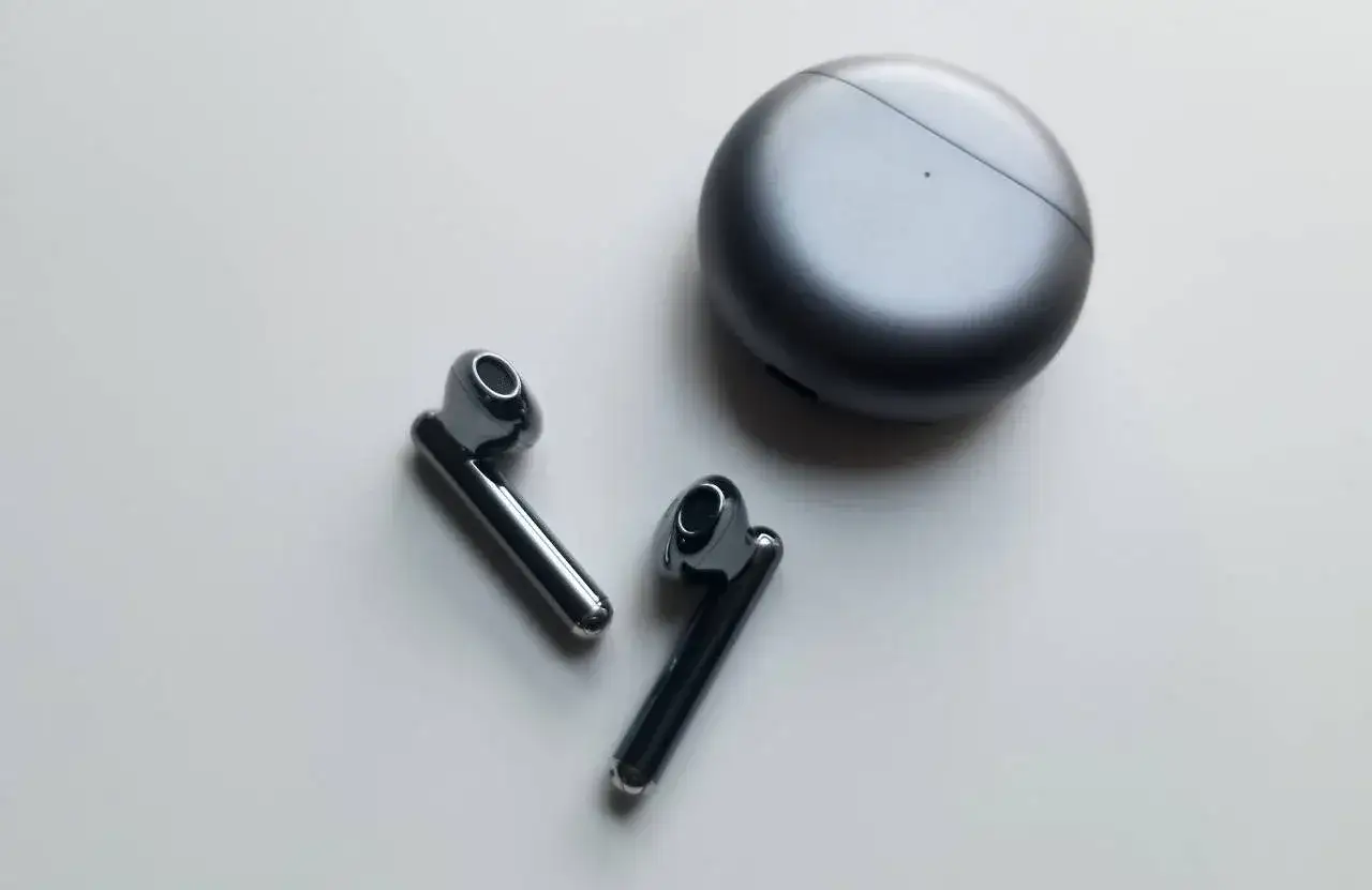 Słuchawki Huawei FreeBuds i ich etui ładujące. Dowiedz się, jak polaczyc sie z sluchawkami Huawei FreeBuds, aby cieszyć się muzyką.
