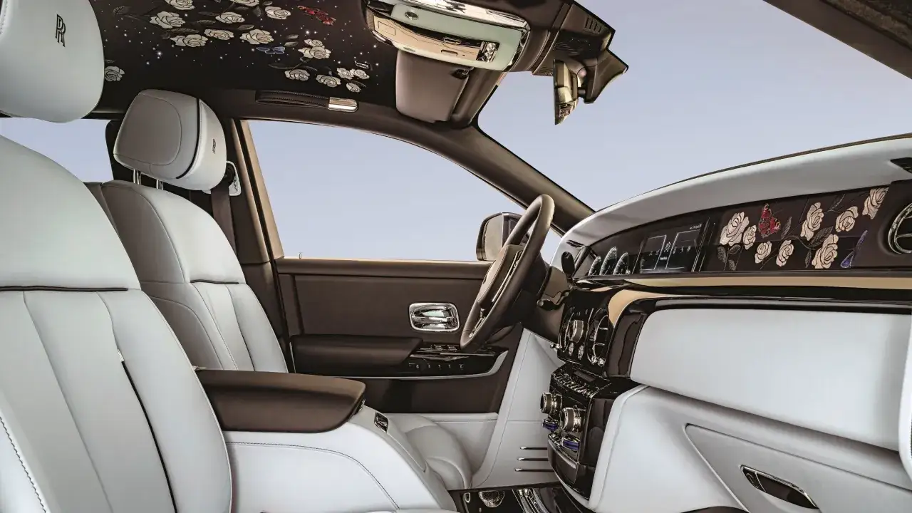 Luksusowe wnętrze Rolls-Royce Phantom z białymi skórzanymi fotelami i podsufitką ozdobioną kwiatami. Zastanawiasz się nad rolls royce phantom cena?