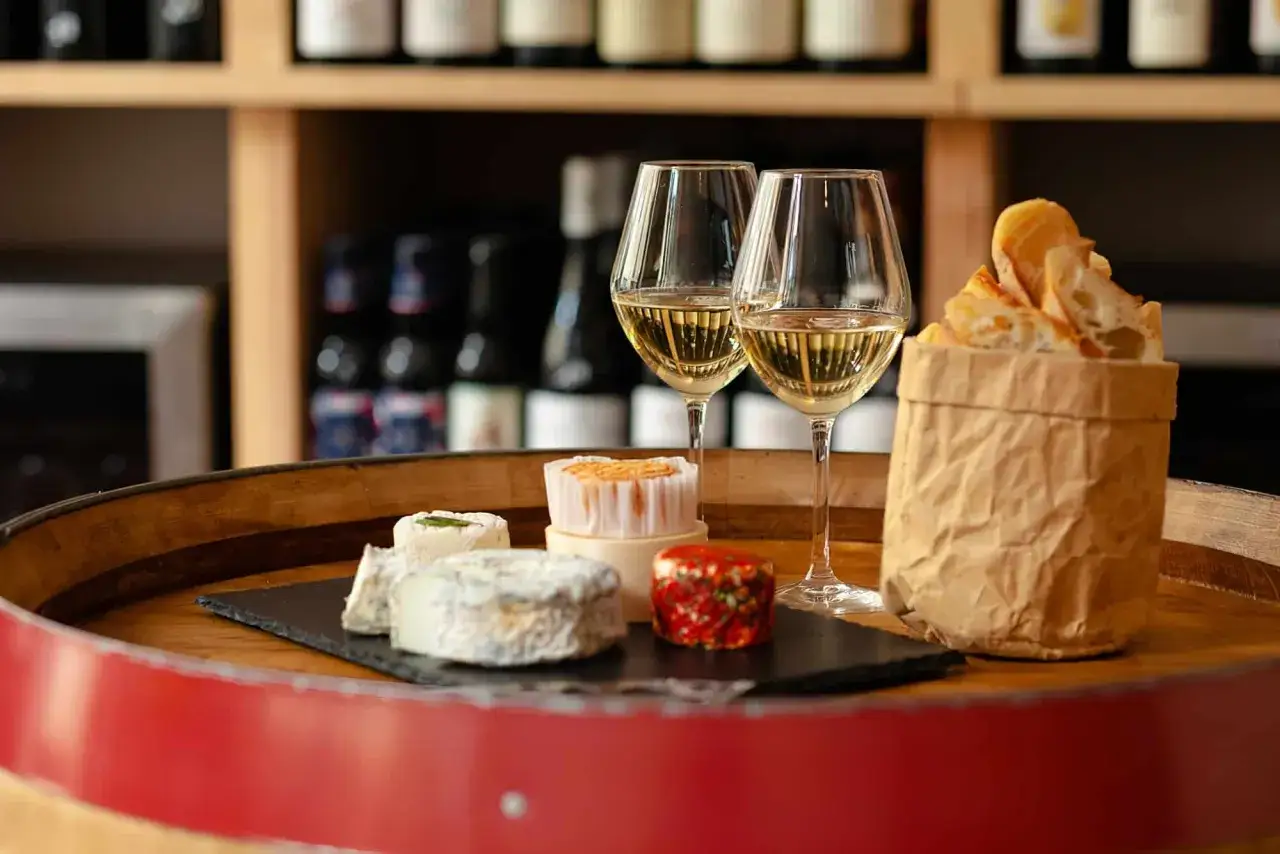 Dégustation de vin parisien avec fromages et pain croustillant sur un tonneau.