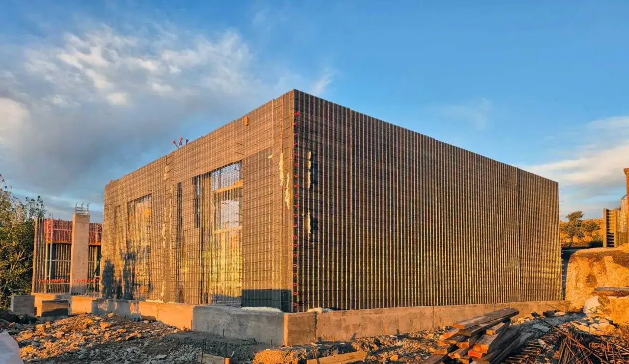 Edificio en construcción con paredes de malla metálica, un ejemplo de construcción industrializada.