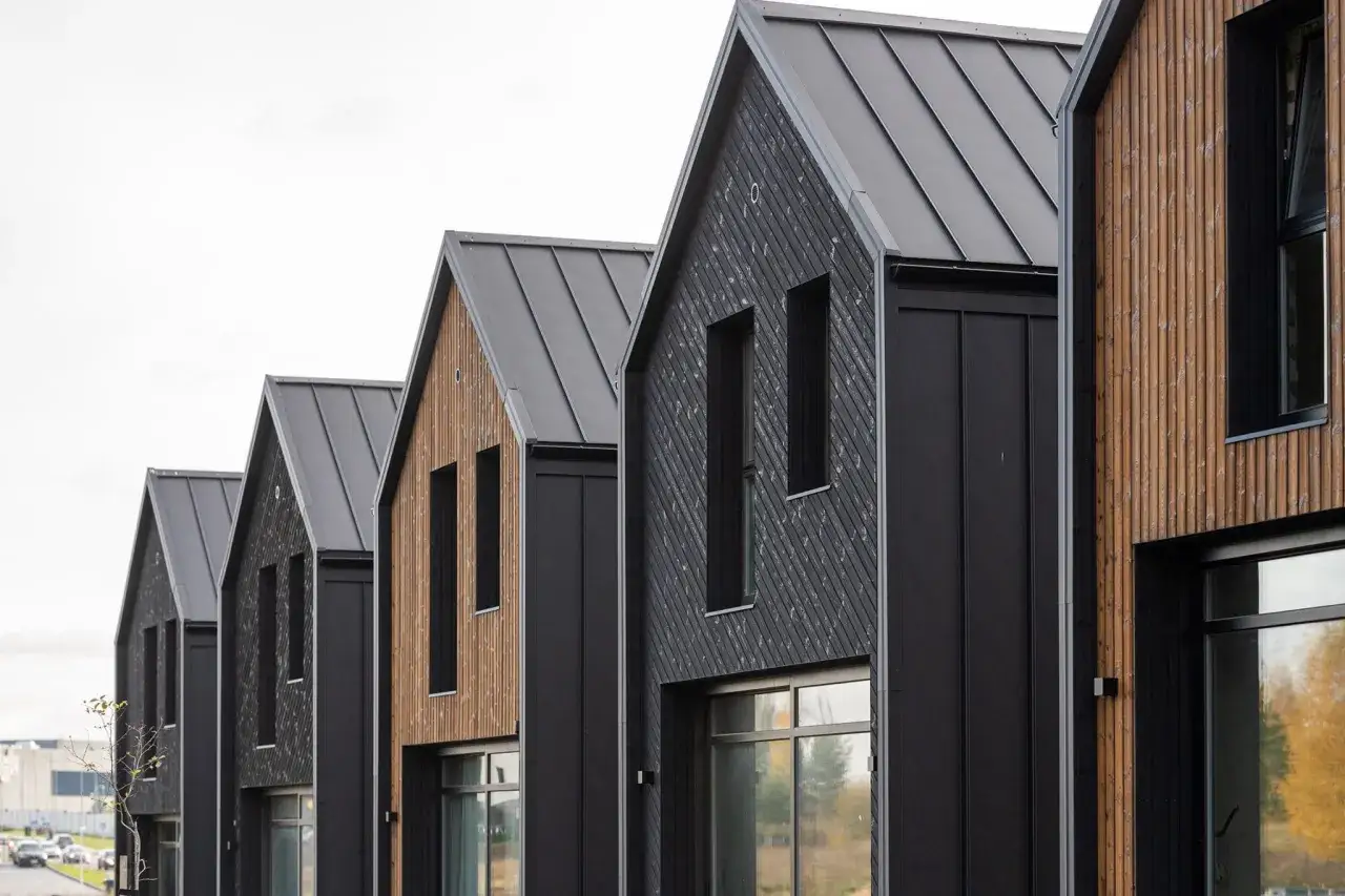 Moderne Reihenh&auml;user mit dunkler Fassade und Holzverkleidung. Gute **estateguru erfahrungen** sind hier sicher, wenn man in solche Objekte investiert.