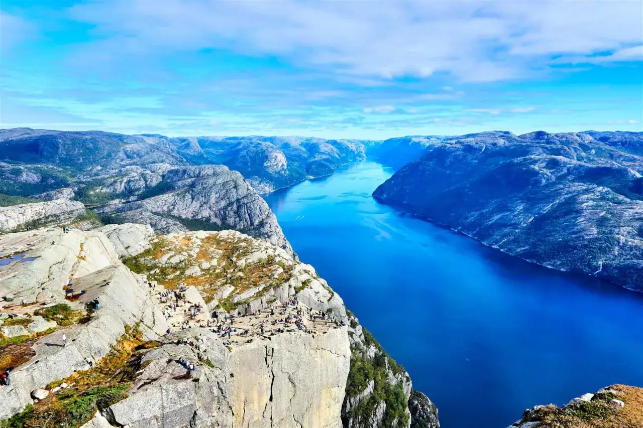 Vacker utsikt över en fjord i Norge, perfekt för camping. Människor njuter av den dramatiska klippan och det blå vattnet.