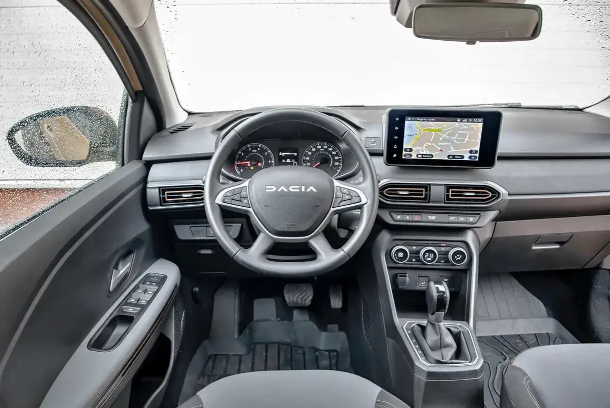 Wnętrze Dacia Sandero 2025 z ekranem nawigacji, kierownicą i panelem klimatyzacji.