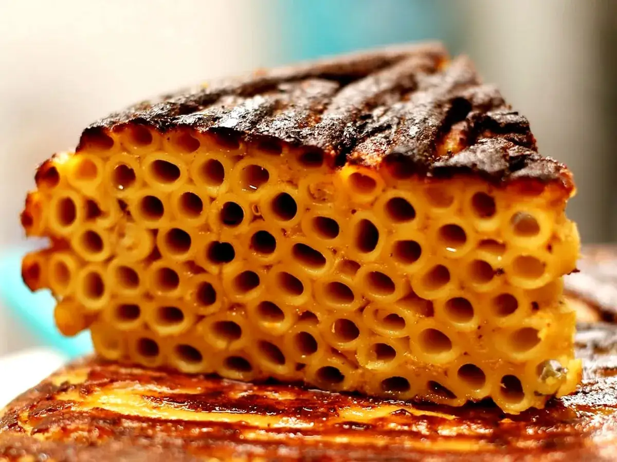 Una fetta di frittata di maccheroni dorata e croccante, con la pasta disposta in un motivo geometrico perfetto.