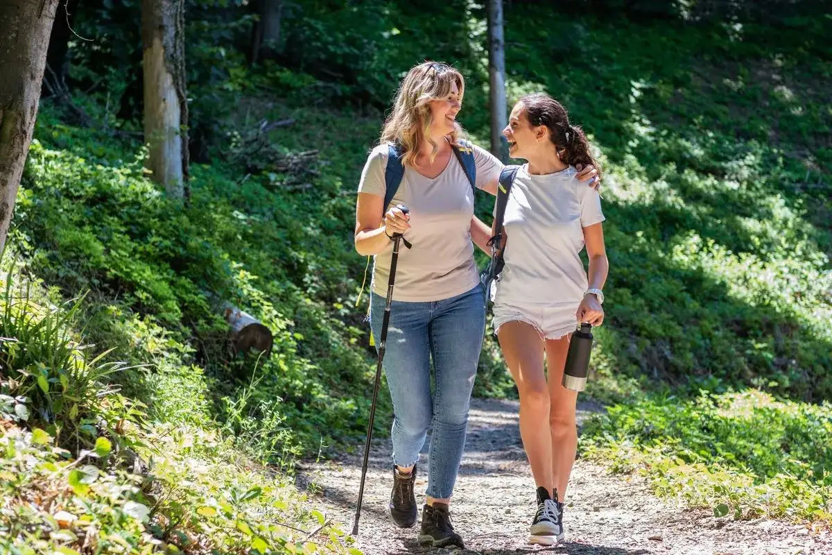 Tv&aring; kvinnor vandrar glatt i skogen, deras gemenskap visar mental styrka.