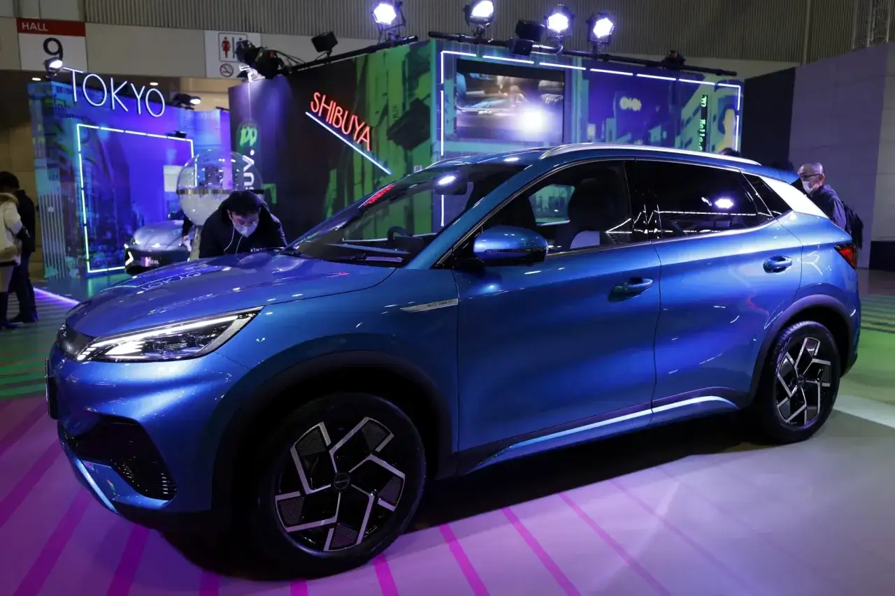 Bl&aring; elbil fr&aring;n BYD, en ny modell som visas upp f&ouml;r potentiella byd &aring;terf&ouml;rs&auml;ljare. Bakgrunden har neonljus med texten 