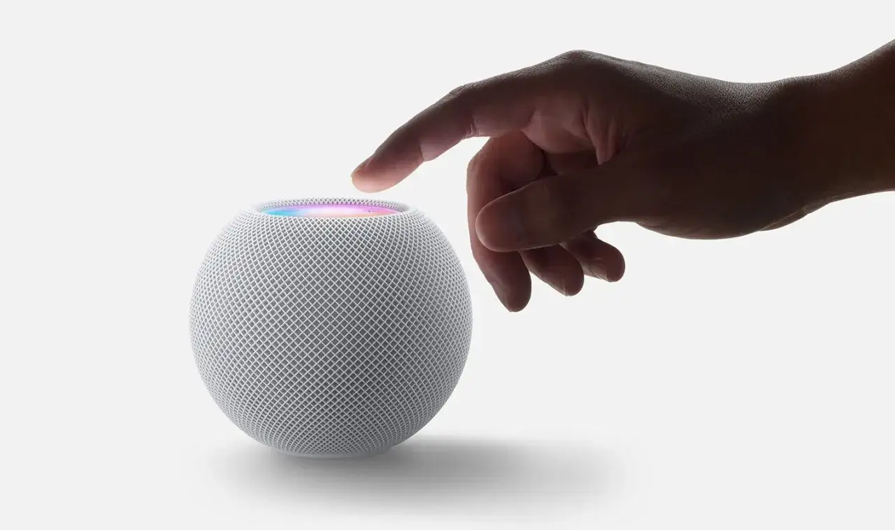 Ein Finger ber&uuml;hrt den HomePod Mini, der leuchtet. Er zeigt, was Siri alles kann, von Musik bis Smart Home.