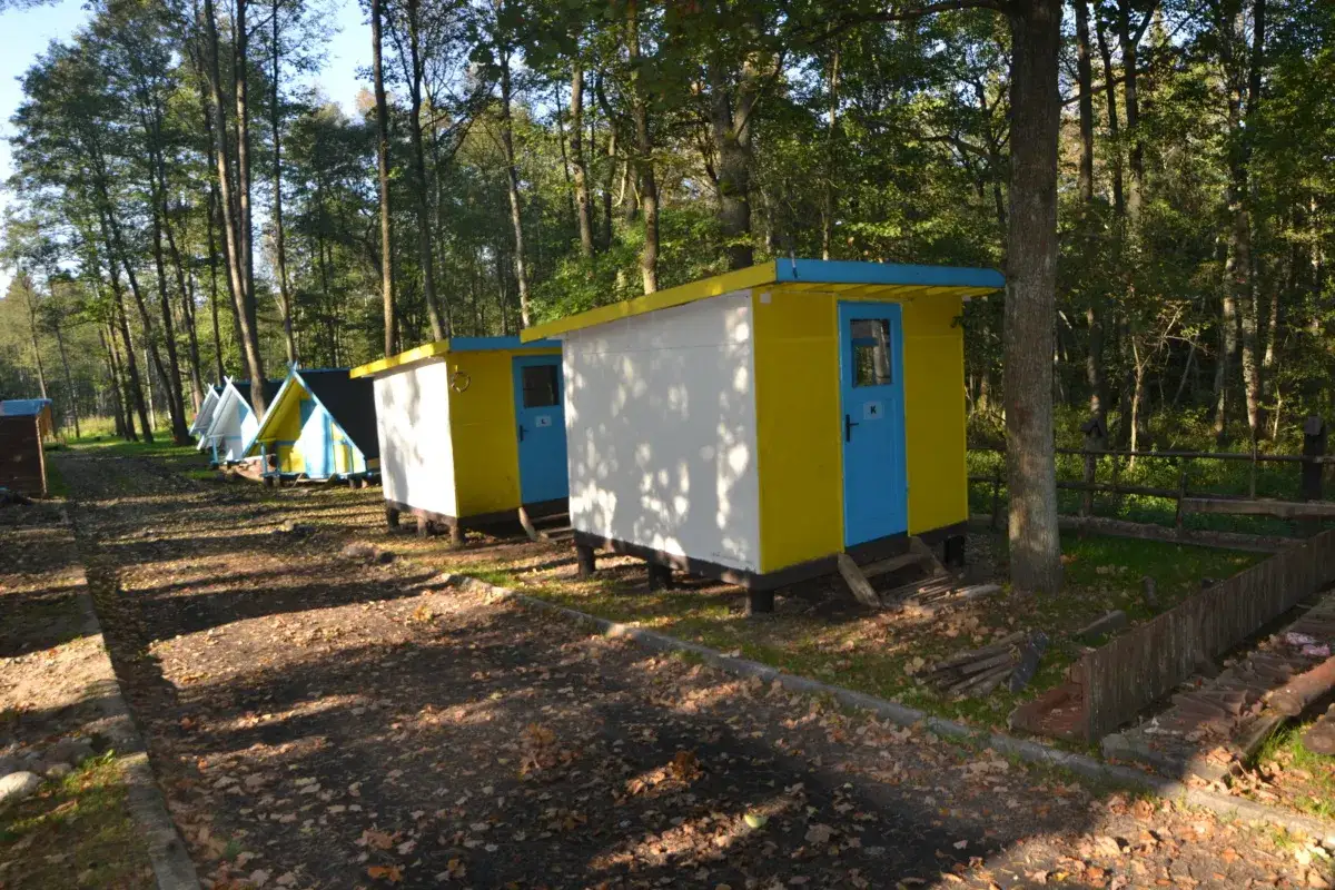 Kolorowe domki kempingowe w lesie, jak perła Krutyni, zapraszają na wypoczynek.