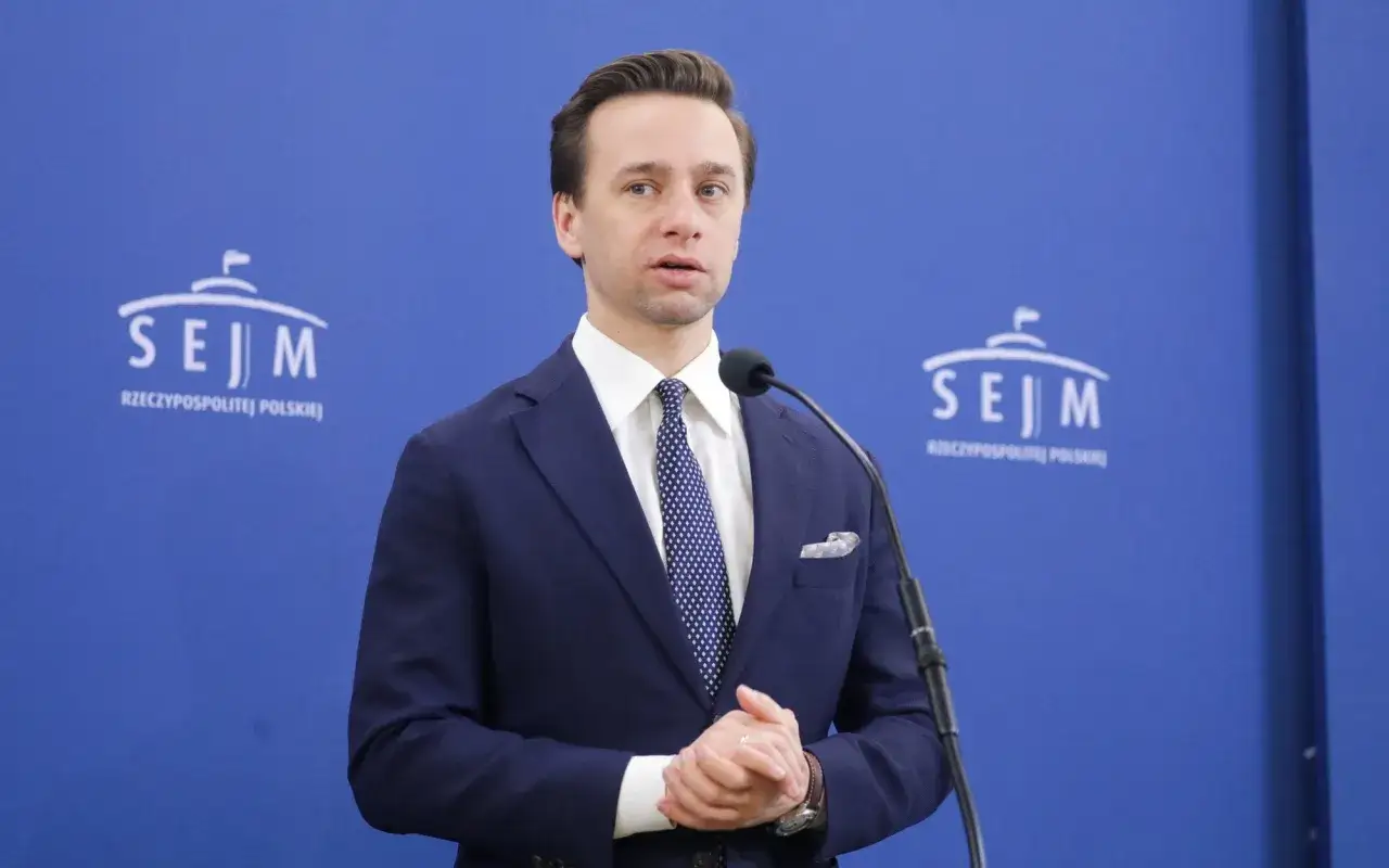 Mężczyzna w garniturze przemawia przy mikrofonie na tle logo Sejmu. Może to być polityk z Konfederacji Wolność i Niepodległość.