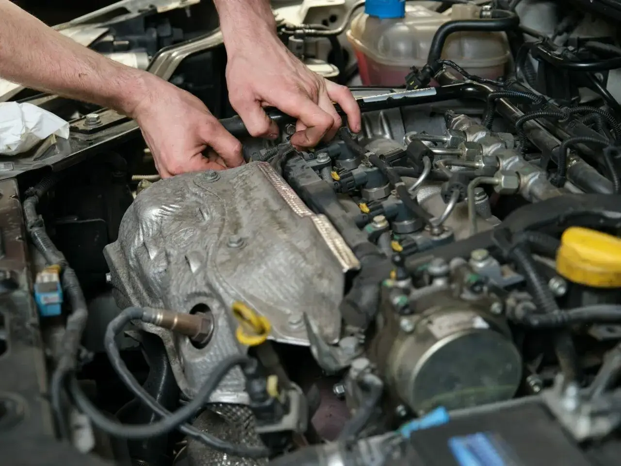 Mechanik pracuje przy silniku, szukając czujnika położenia wałka rozrządu.