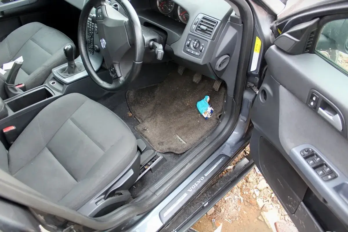 Wnętrze Volvo S40 II z widocznym siedzeniem, kierownicą i dywanikiem z niebieskim opakowaniem.