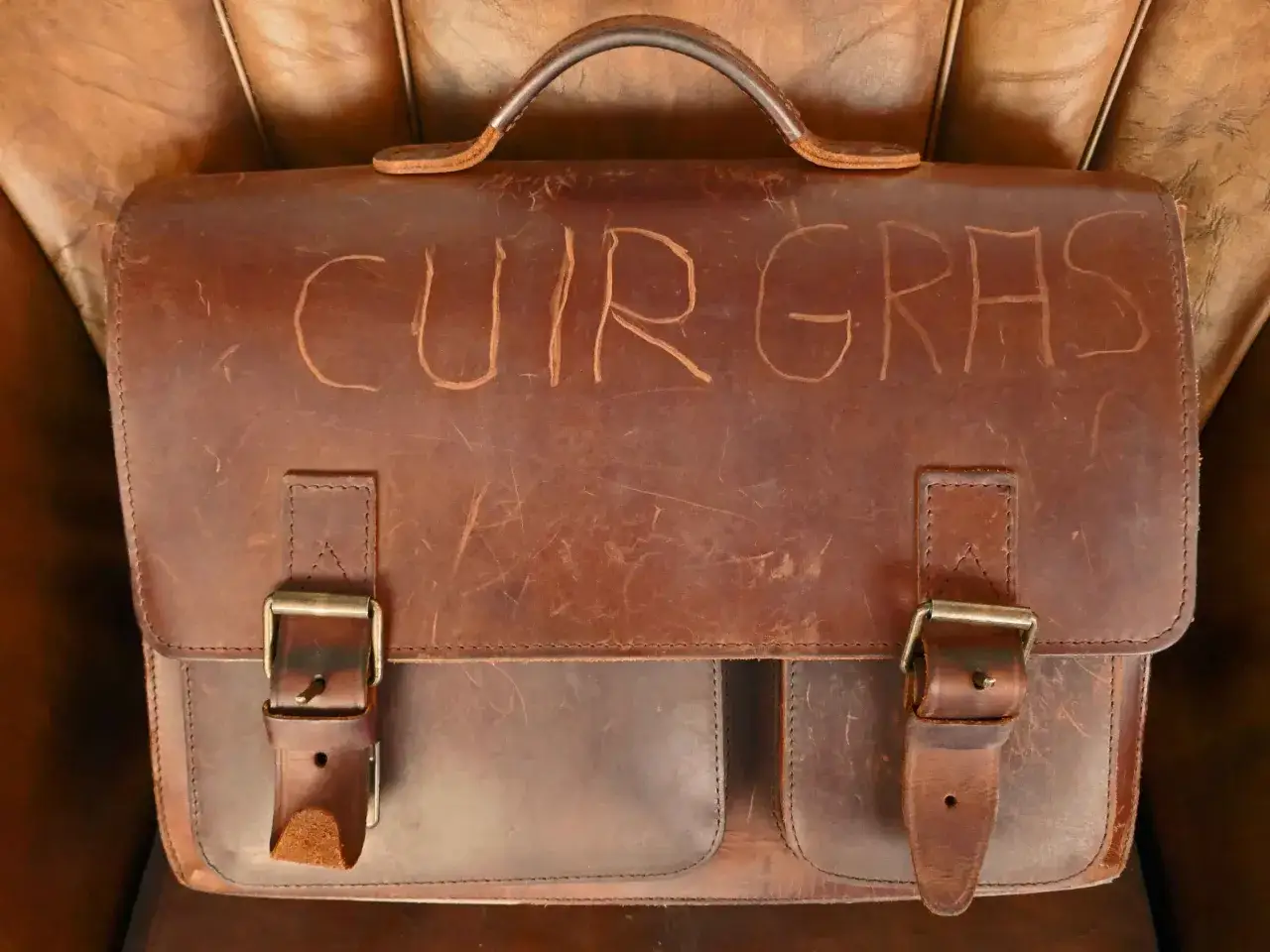 Sacoche en cuir gras us&eacute;, avec le texte 