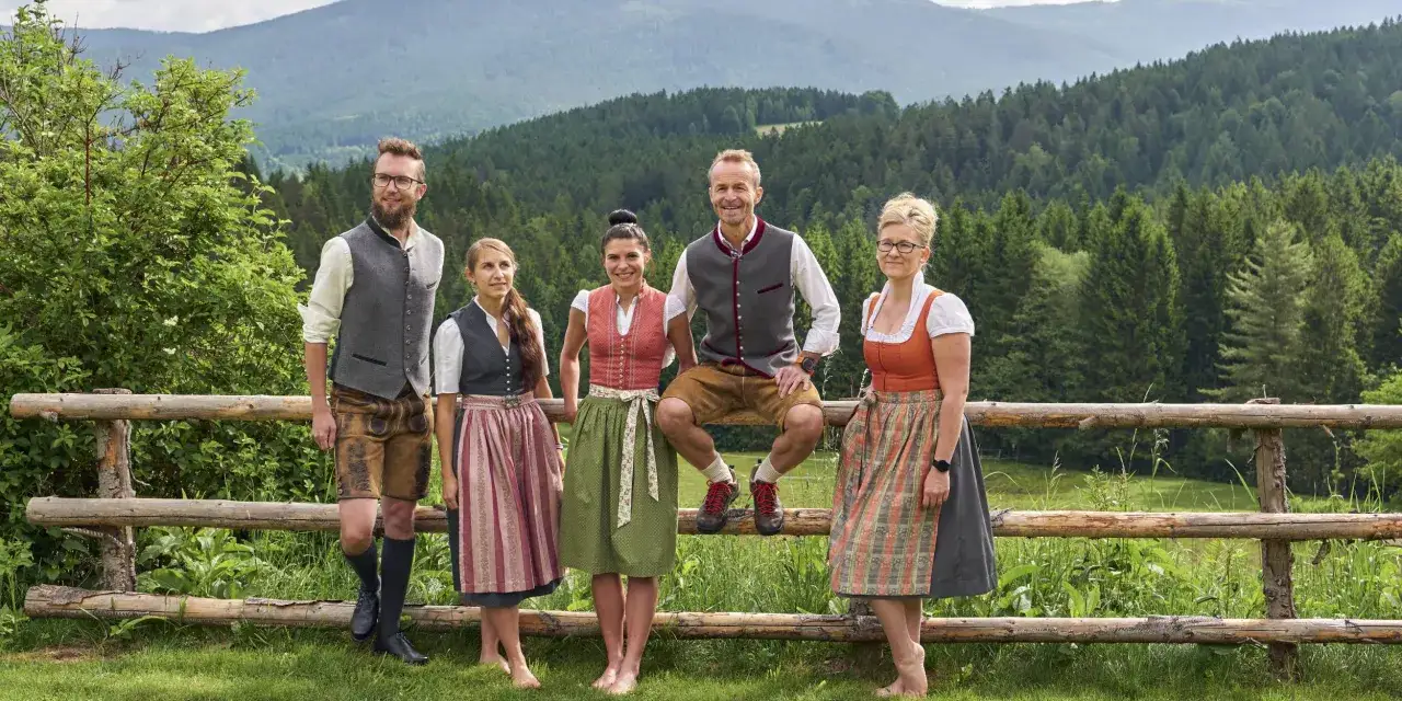 F&uuml;nf Personen in traditioneller Chiemgauer Tracht stehen vor einer Bergkulisse.