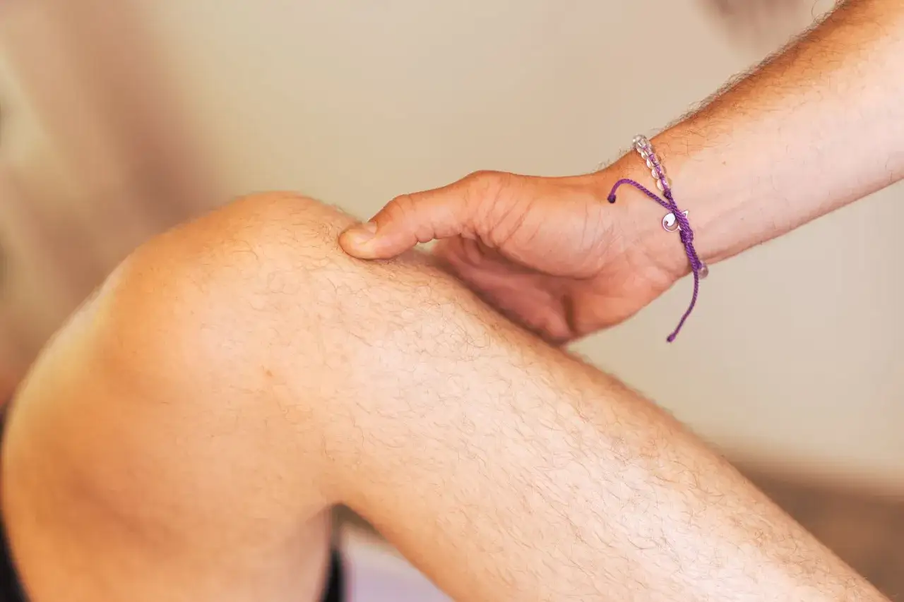 Ein Finger tastet das Knie ab, um mögliche Symptome einer Schleimbeutelentzündung zu erkennen.