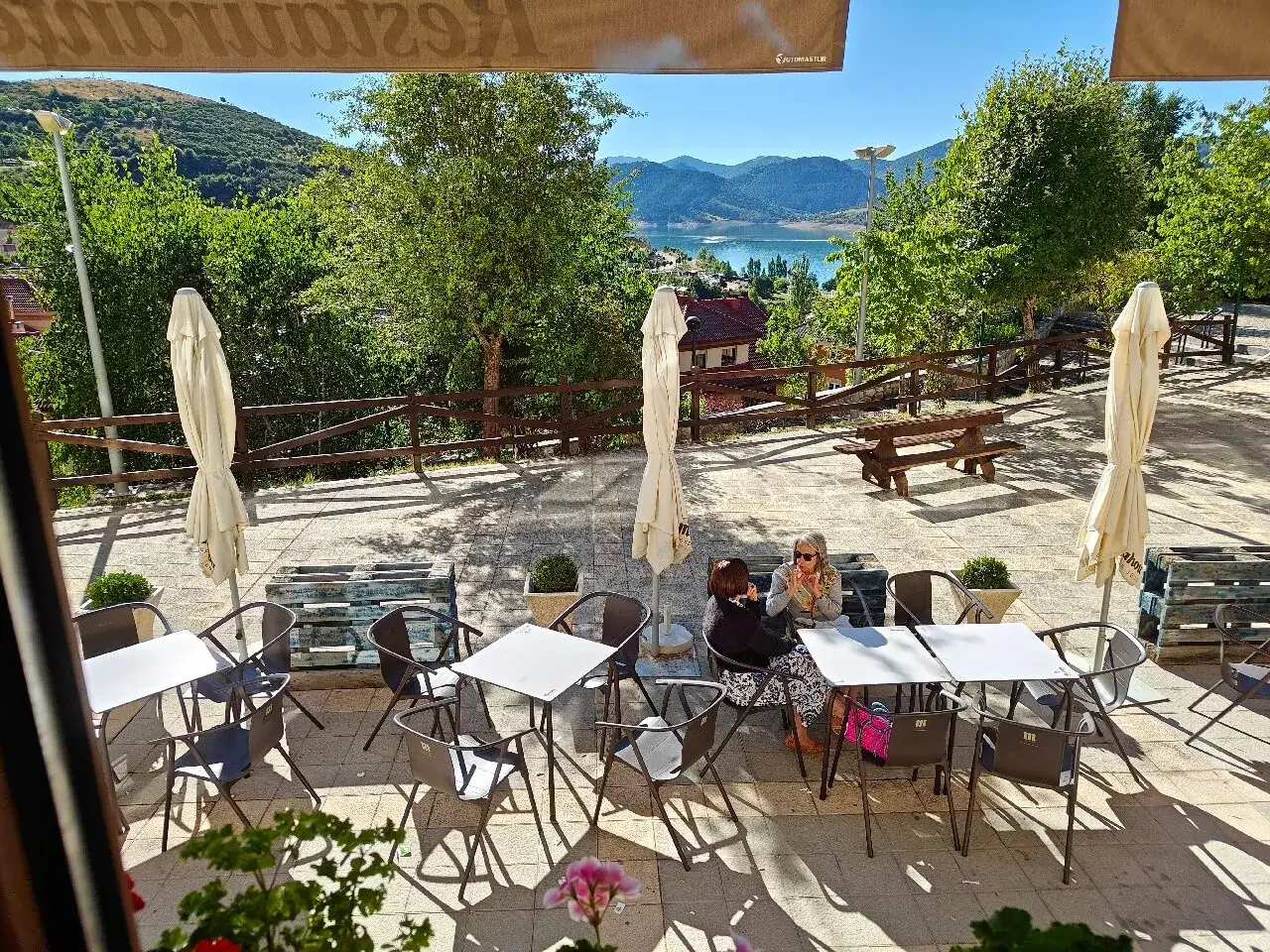 Terraza de restaurante con vistas al embalse. Ideal para saber donde comer en Riaño. Mesas, sillas y sombrillas preparadas.