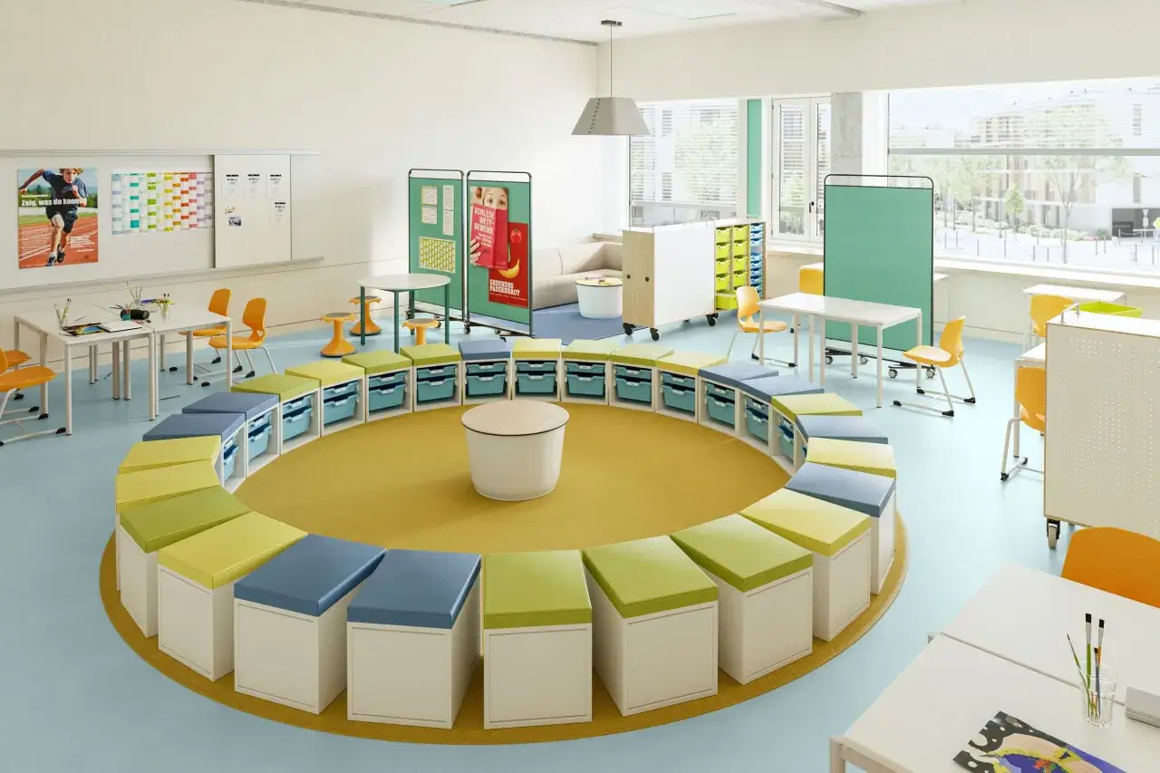 Ein heller, moderner Klassenraum im Churer Modell mit runden Sitzgelegenheiten, Tischen und viel Stauraum.