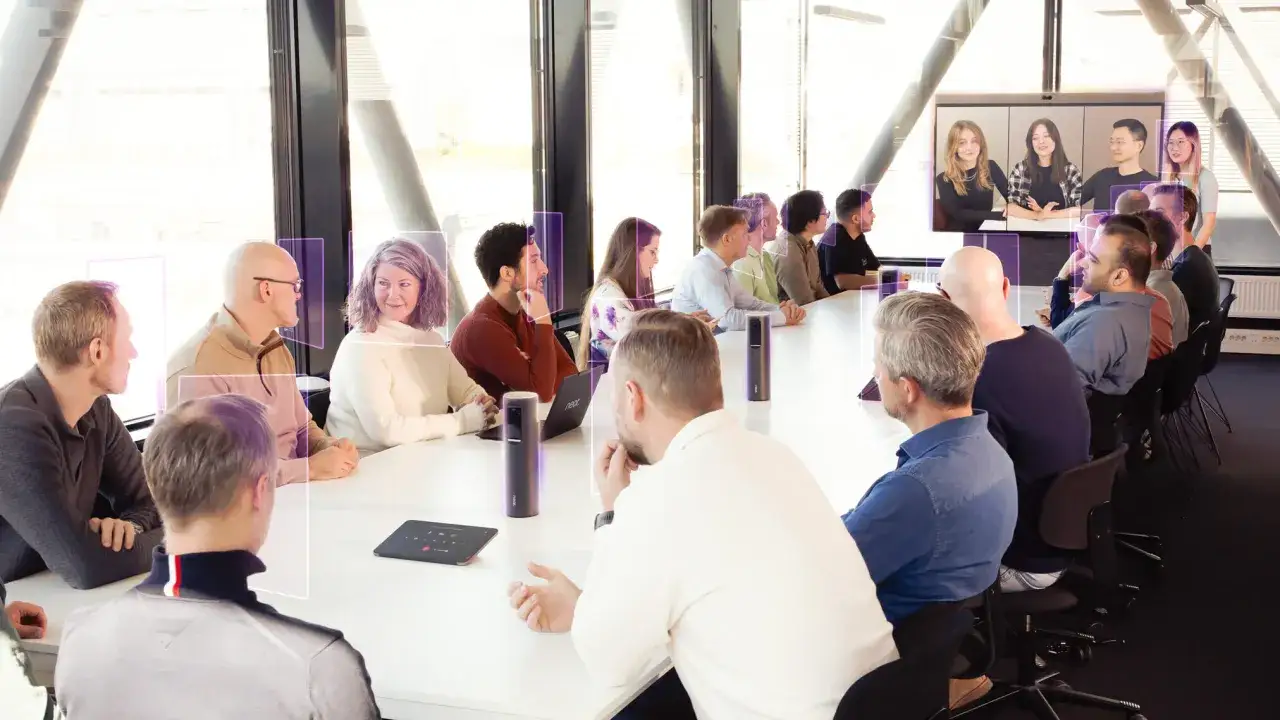 Teilnehmer eines Software Architecture Summit in einem modernen Konferenzraum, die per Videokonferenz verbunden sind.