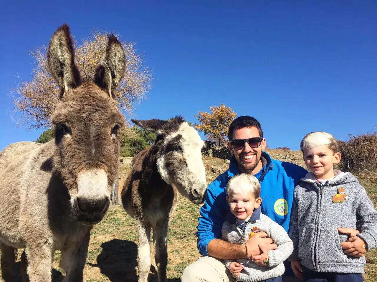 Familia disfrutando del turismo interior España, con burros y niños en un día soleado.