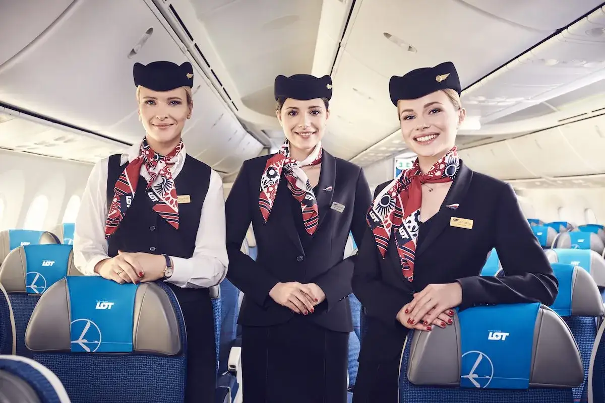 Trzy uśmiechnięte stewardessy LOT w eleganckich mundurkach. Zastanawiasz się, ile zarabia stewardessa?