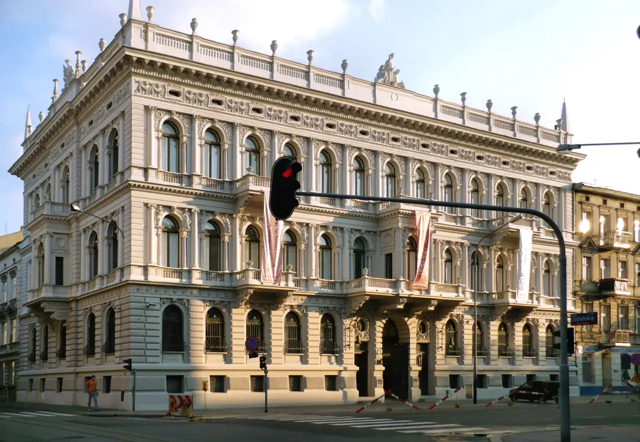 Elegancki budynek muzeum sztuki w Łodzi z ozdobnymi fasadami i rzeźbami na dachu.
