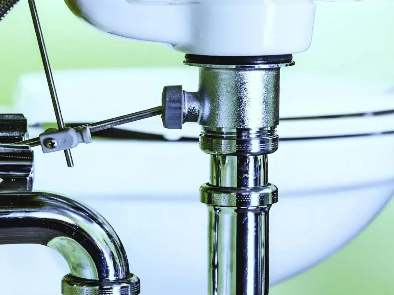 Plomberie sous un lavabo, avec un outil pour d&eacute;boucher canalisation eau chaude.