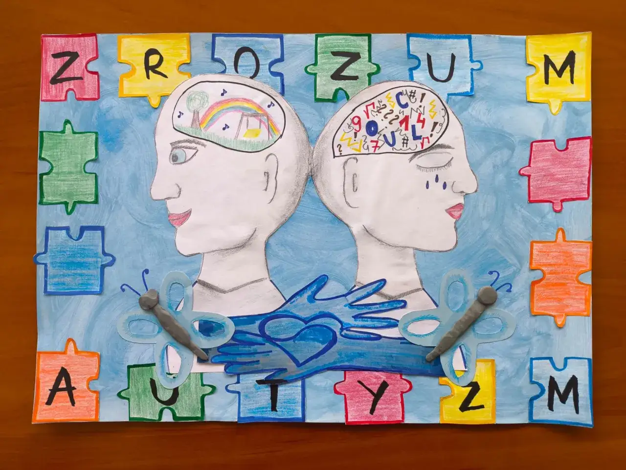 Dwie głowy, jedna z tęczą, druga z symbolami, otoczone puzzlami. Obraz symbolizuje maskowanie autyzm i potrzebę zrozumienia.
