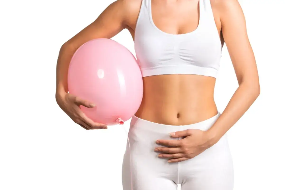 Donna con palloncino rosa sull'addome, simbolo di gonfiore e problemi di digestione.