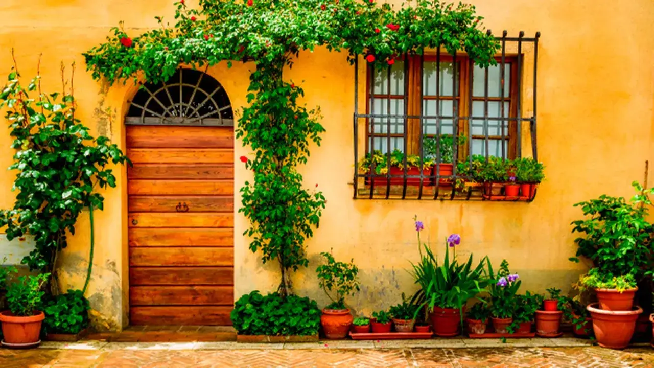 Fachada amarilla con puerta de madera y ventana adornada con flores. ¡La mejor época para pintar la casa es cuando la naturaleza te inspira!