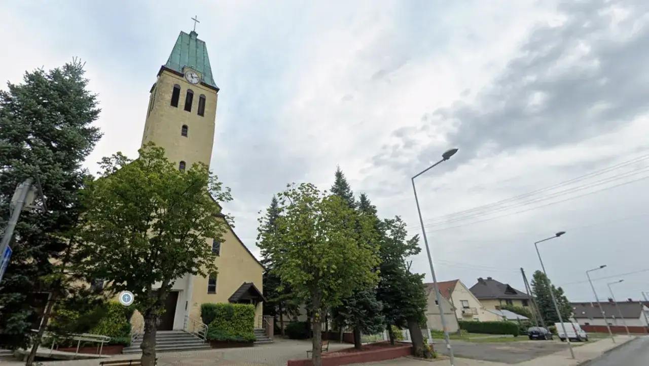 Żółty kościół z zieloną wieżą i zegarem. Zastanawiasz się, ile kosztuje msza w intencji zmarłego?