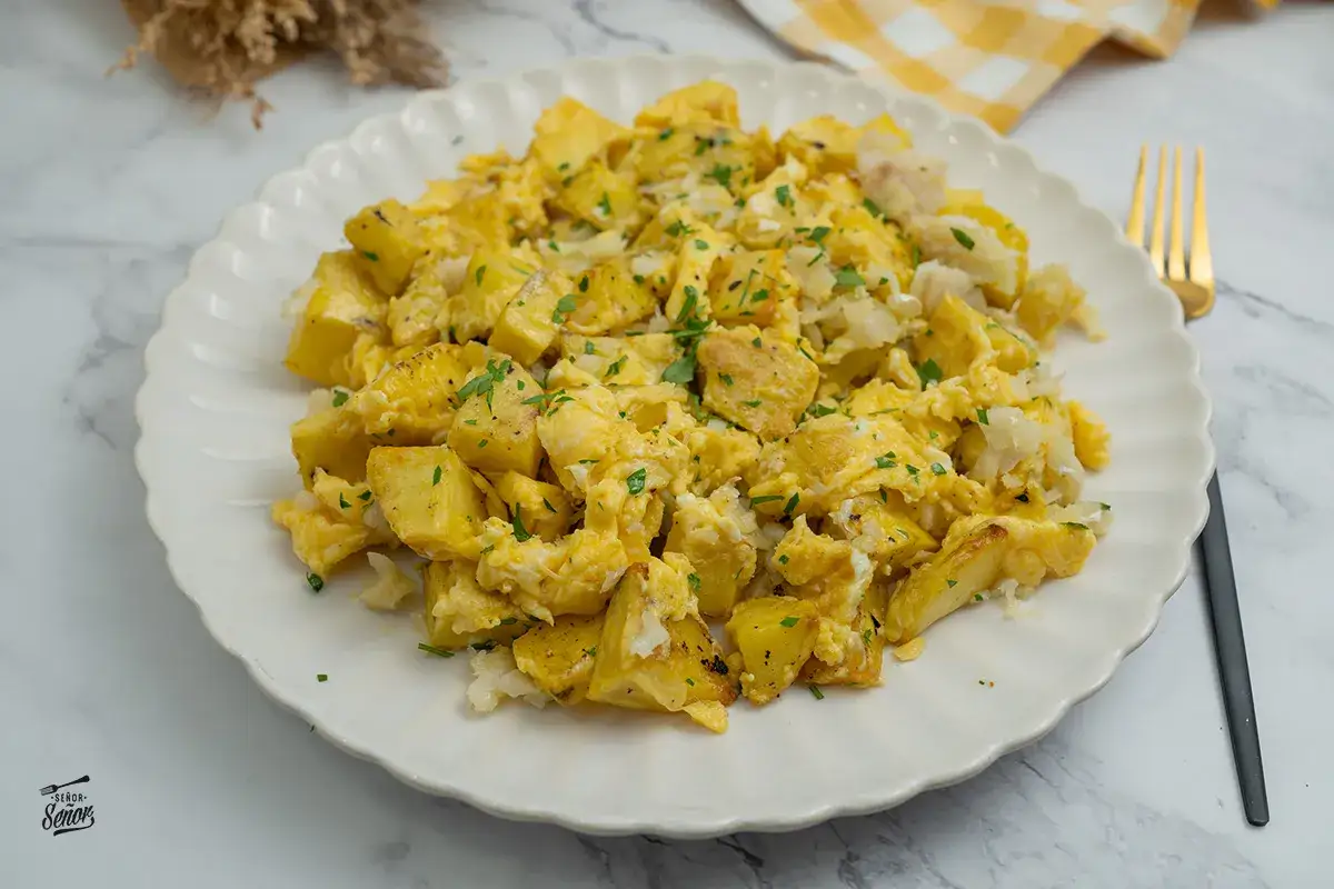 Un delicioso revuelto de bacalao con patatas, espolvoreado con perejil fresco. Un plato casero y reconfortante.