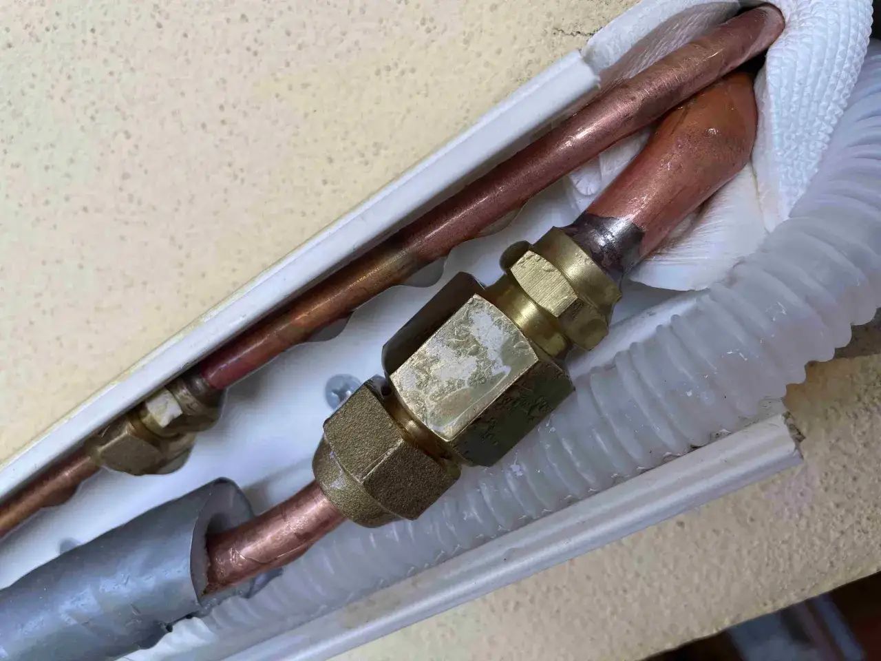Tubazioni in rame di un condizionatore, con raccordi in ottone. Segni di condensa potrebbero indicare come capire se manca gas condizionatore.