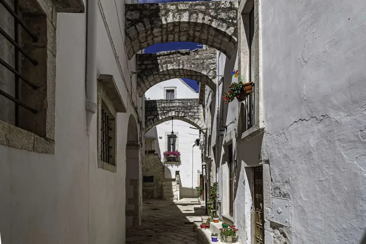Un vicolo suggestivo tra i borghi puglia, con archi in pietra e case bianche adornate da fiori.