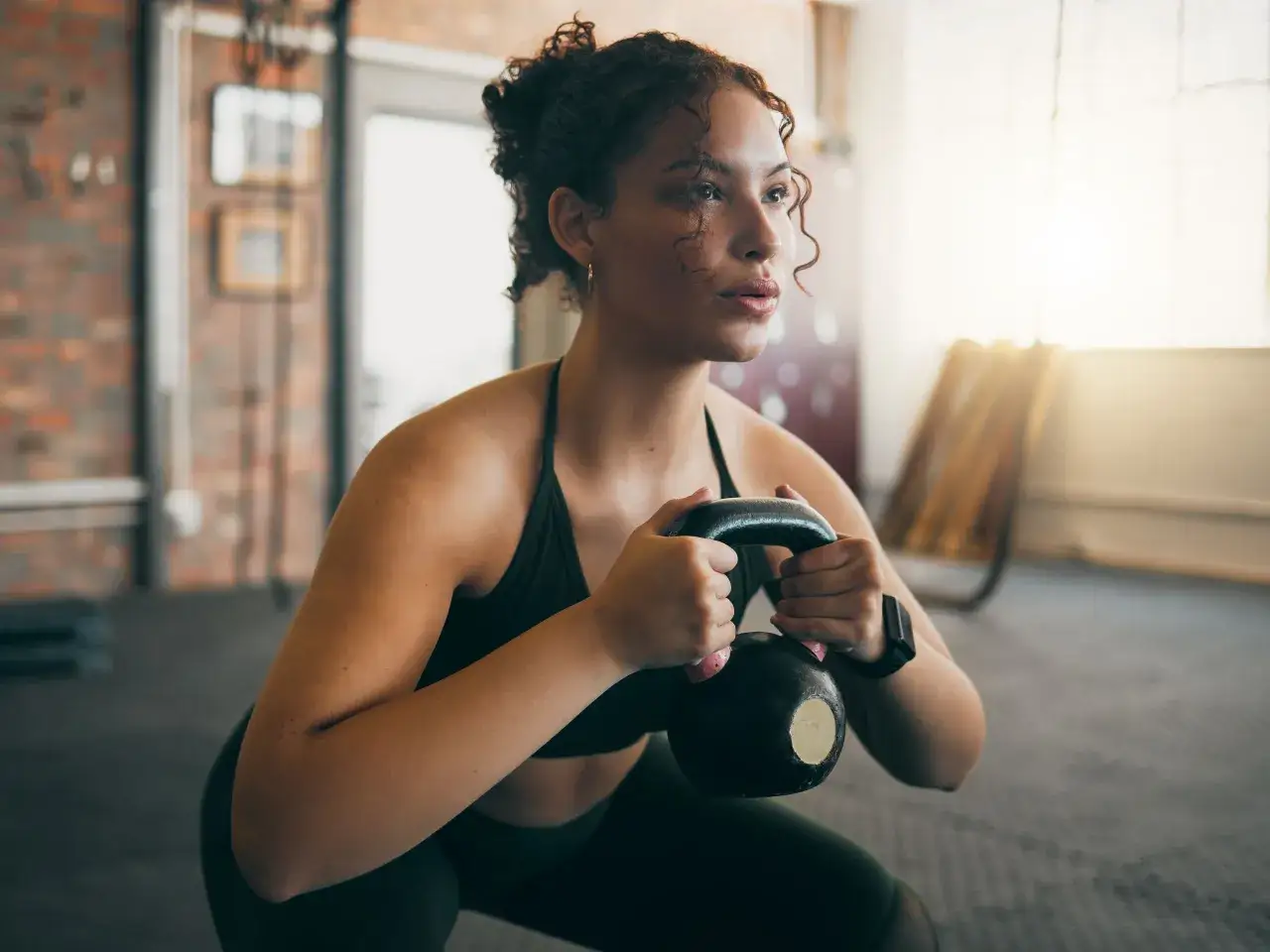 Femme faisant un squat avec kettlebell, un exercice efficace pour le cardio ou la musculation pour maigrir.