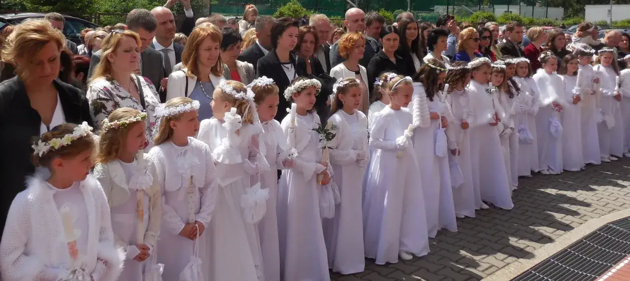 Dzieci w białych strojach, z wiankami na głowach, trzymają świece. To piękny dzień, kiedy jest komunia święta.