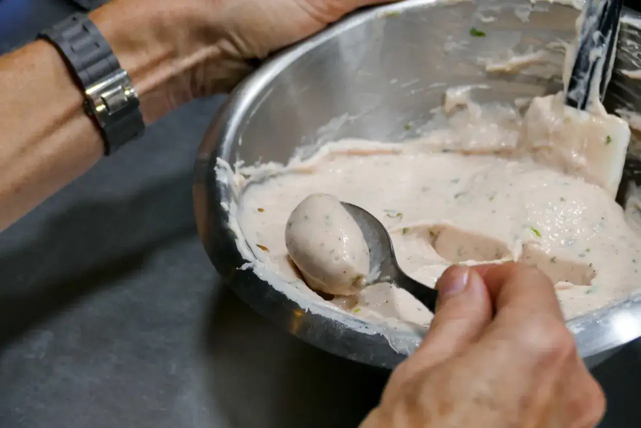 Une cuill&egrave;re pr&eacute;l&egrave;ve une quenelle de glace cr&eacute;meuse dans un bol.