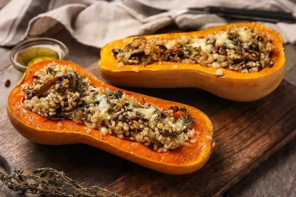Id&eacute;es pour que faire avec des butternut : courges r&ocirc;ties farcies au riz, champignons et fromage fondant, sur une planche en bois.