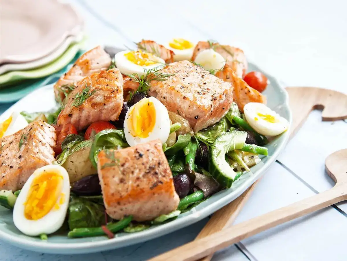 En härlig sommarmat recept: grillad lax med ägg, gröna bönor och tomater på en tallrik.
